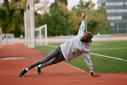 Black man doing side plank exercise on stadium track