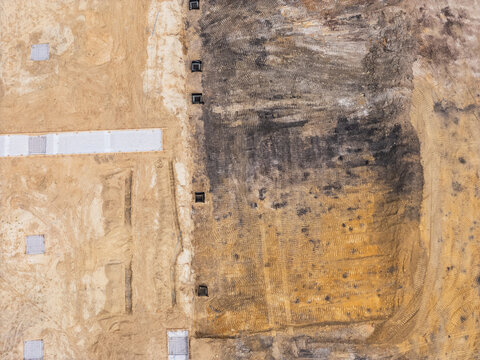 Aerial view of a construction site showing cleared land, soil excavation, and concrete foundation footings in Leland, North Carolina, United States.