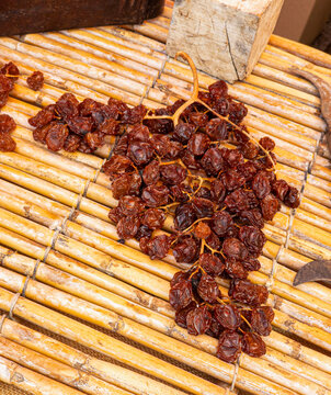 Close up view of dark brown raisins made with traditional Spanish escaldado process on rustic cane mat