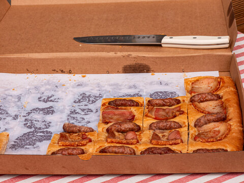 Large cardboard pizza box with traditional Spanish savory pie filled with sausages and pork belly ready for serving