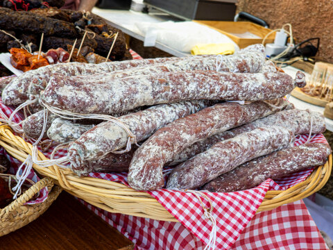 Rustic display of cured sausages and meat delicacies in a woven basket at a farmers market