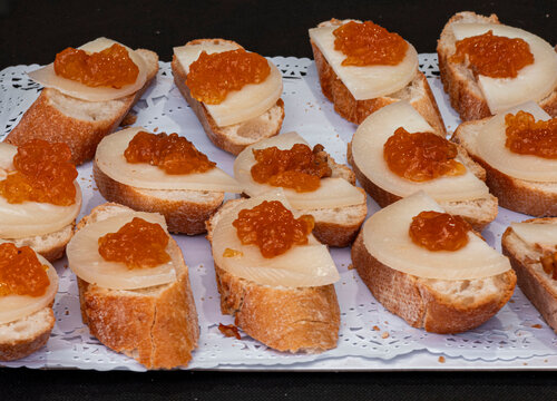 Sliced baguette topped with manchego cheese and peach jam served on a paper lace tray