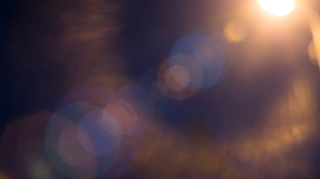 Abstract Dreamy Lens Flare Background with Circular and Hexagonal Light Artifacts on Dark with Gold to Blue Halation