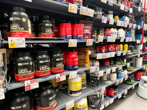 Variety of dietary supplements and protein powders, vitamins on shelves in a modern health food shop, lifestyle fitness products and bodybuilding nutrition arranged on supermarket display. 