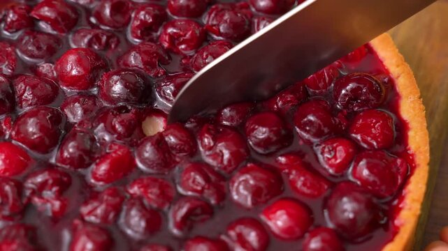 Cutting a cherry tart with a knife, slice of berry pie