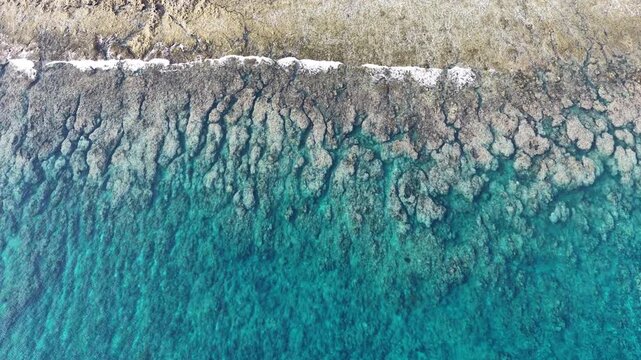Calm seas wash against the beautiful coastline of the remote Maju Island in the Molucca Sea, Indonesia. A rugged, rocky reef surrounds this tropical paradise which few people ever visit.