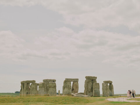 Visitors gather at the prehistoric stone circle of Stonehenge under dramatic clouds on Salisbury Plain, Wiltshire, England.
