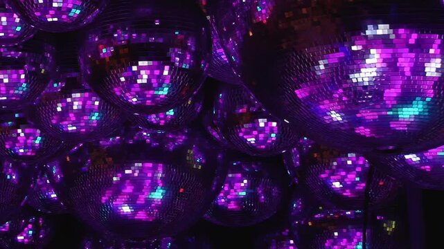 Gold and Green Reflections Across Mirrored Disco Balls. Reflective spheres fill the dark interior while tiled mirror surfaces scatter changing light into colorful abstract patterns.