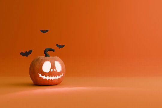 A glowing jack-o'-lantern with a wide grin and large eyes sits on a solid orange surface, below three dark bat silhouettes. A modern, minimalist Halloween scene with ample copy space.