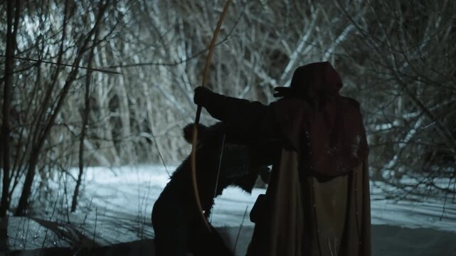 Werewolf attacked by archer wearing dark hood. Werewolf lunges at target as human draws bow then falls to ground after apparent hit. Snowy forest with bare trees and dim lighting