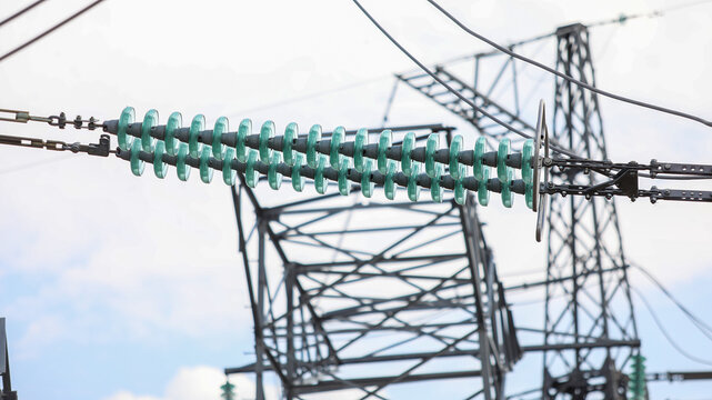Glass insulators separating high voltage power lines on an electricity pylon, symbolizing energy transmission, infrastructure, and the distribution network