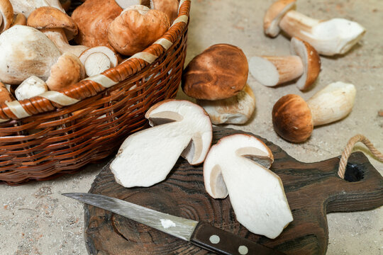 Single porcini mushroom cut lengthways and knife on wooden board for recipe blogs, vegetarian menus, ingredient lists, cooking classes. Real Photo