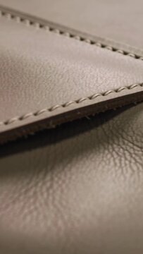 Vertical video: Starting camera tracking leather seam in shop checking patch, stitch, suede nap