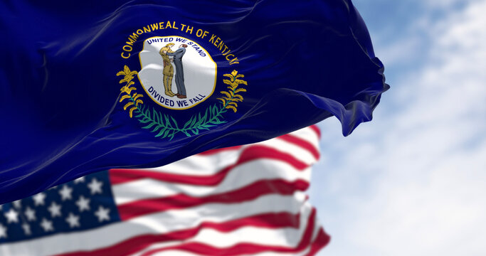 Kentucky state flag and the American flag waving in the wind on a clear day