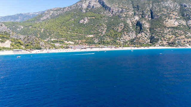 Aerial view of the turquoise waters and sandy coastline of Oludeniz beach backed by steep green mountains Oludeniz, Mugla, Turkiye.