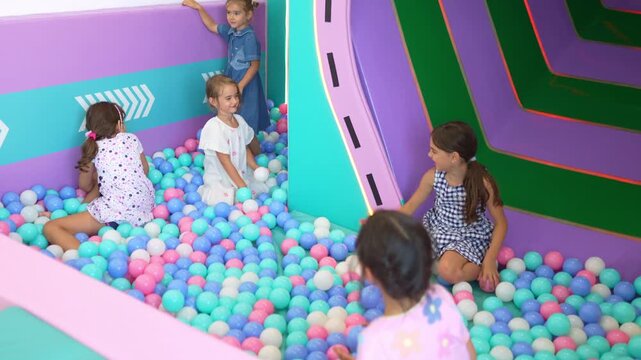 Cheerful children friends enjoying leisure time in a modern indoor playground with colorful balls