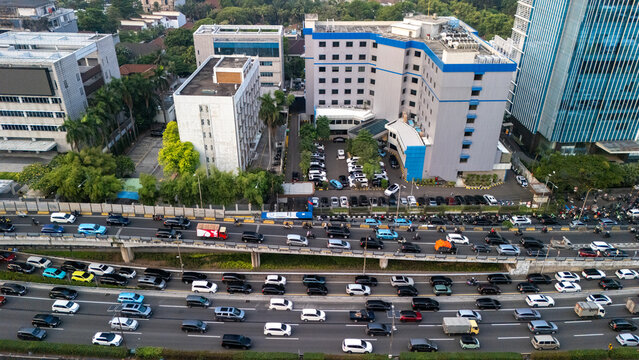 Aerial view of Jakarta busy transportation corridor with multilane roads, elevated ramps and heavy traffic in a dense city district.