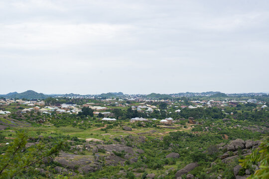 Aerial view of Lamingo area with rocky terrain, lush greenery, and residential houses under a cloudy sky in Jos, Plateau, Nigeria.