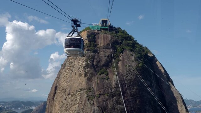 POV from inside a cable car approaching the Sugarloaf Mountain on a sunny day in Rio de Janeiro, Brazil.