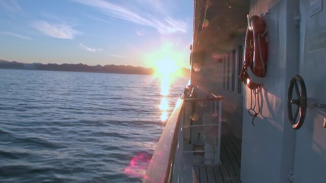 Arctic Ocean Ship Crossing Cold Arctic Ocean in Northern Seas. Railing and deck elements frame the view while cold water stretches toward the distant polar horizon.