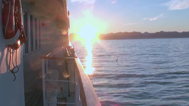 Arctic Ocean Ship Crossing Grey Ocean Waters Across Polar Seas. Railing and deck elements frame the view while cold water stretches toward the distant polar horizon.