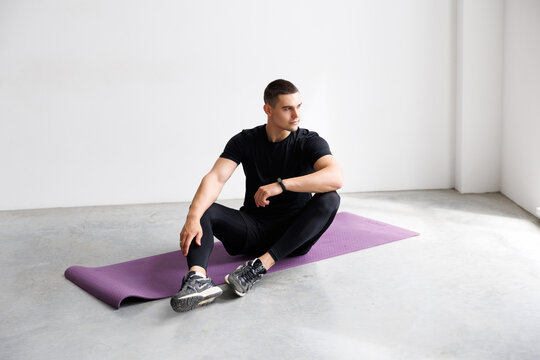 Fitness results. Fit man looking at his smart watch while exercising at home