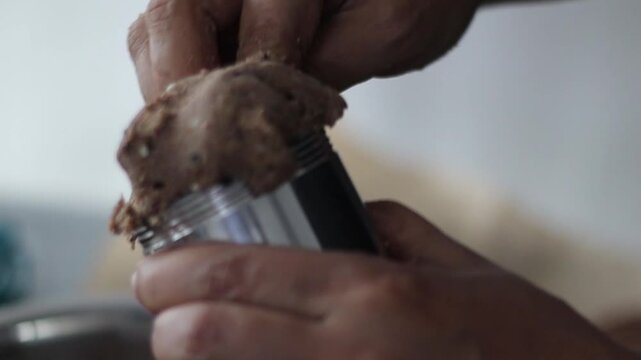 Filling a murukku mould with ragi dough and sesame seeds for a traditional Indian snack