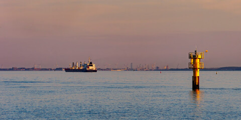 Cargo ship passing navigation buoy at sunset in Zeeland © Luc V. de Zeeuw