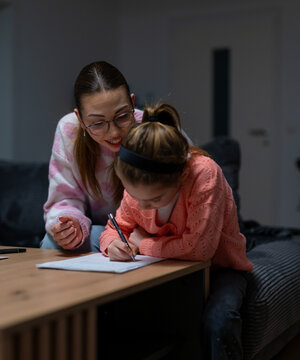 Aunt supervising girl doing homework at home