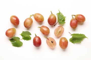 Fototapeta premium Fresh ripe grapes and green leaves on white background, flat lay