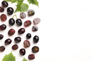 Fototapeta premium Fresh ripe grapes and green leaves on white background, flat lay. Space for text