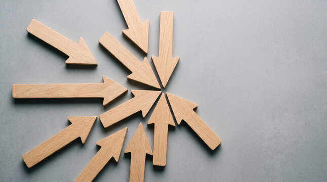Wooden arrows converging toward central point expressing motivated goal achievement and strategic success on grey background