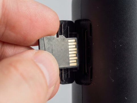 Finger inserting memory card into electronic device with careful precision