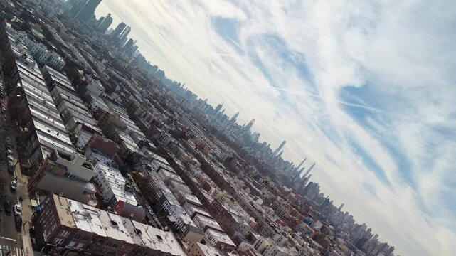 Rolling drone view of city rooftops and distant skyscrapers. The horizon rotates through a sideways angle to an inverted view of dense rooftops and distant towers. Filmed in Queens NYC.