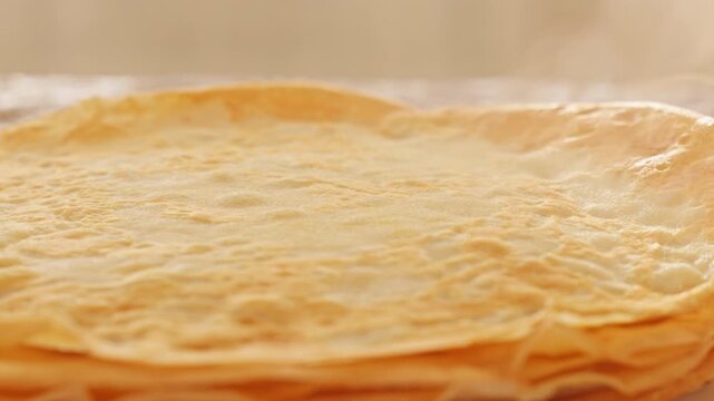 Hot steam rises from stack of fresh homemade pancakes on white plate during detailed slow motion view. Cinematic morning breakfast video footage provides warm cozy asset for design element.