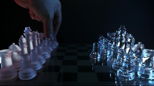 Strategic move of two hands playing in a glass chess game on a dark background.