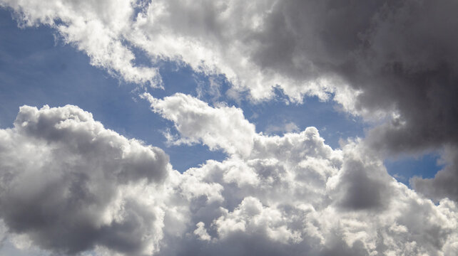 Cielo nublado con nubes blancas y grises iluminadas por la luz del sol