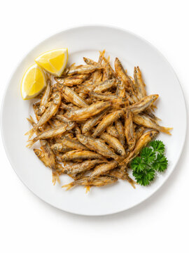 Meefischli mit Zitrone &ndash; fr&auml;nkische Spezialit&auml;t von oben
Goldbraun frittierte kleine Fische mit Zitrone und Petersilie auf einem wei&szlig;en Teller. Ansicht von oben vor einem wei&szlig;en Hintergrund.