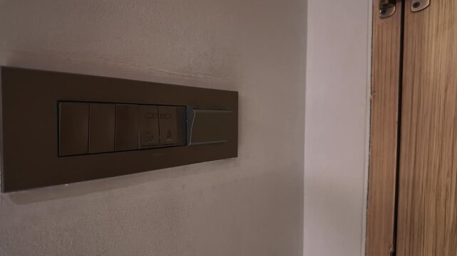 A hotel guest slides a keycard into a wall slot to activate room electricity and lights, illustrating energy-saving hotel technology, guest access control and convenient hospitality services.
