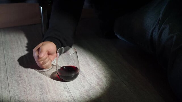 Man's hand reaches for a glass of alcohol.