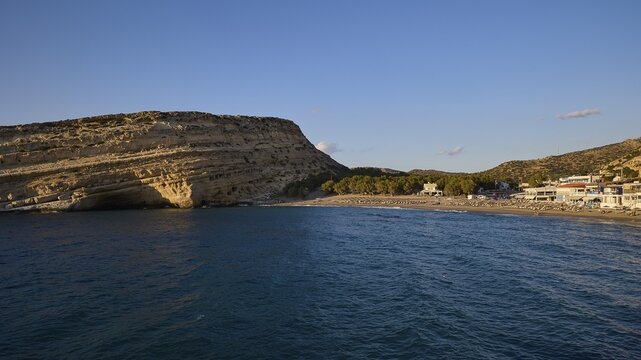 Neolithic caves, former hippie paradise, panoramic view of a beach next to a rocky coast and small buildings, Matala, south coast, Crete, Greek Islands, Greece