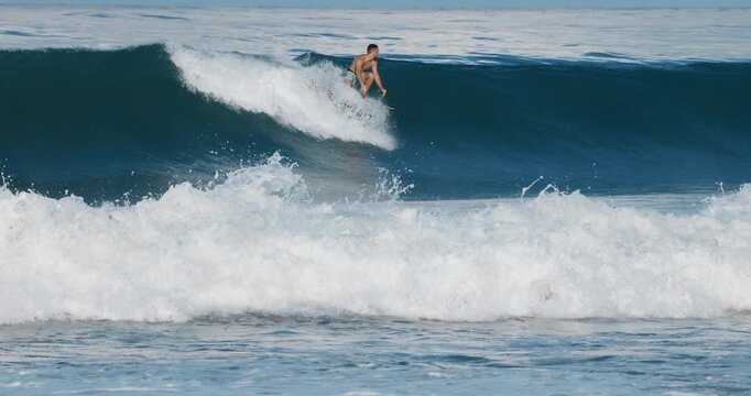 Surfer man rides on surfboard on ocean wave. Summer surfing, slow motion