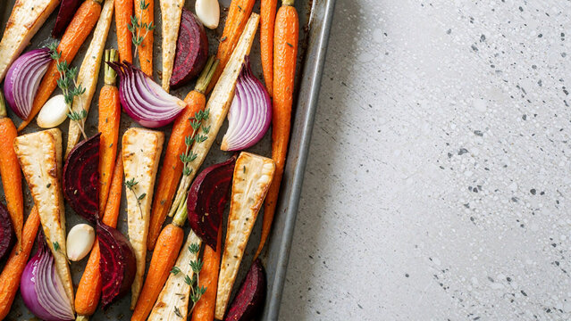 Roasted root vegetables on a sheet pan with copy space, top view
