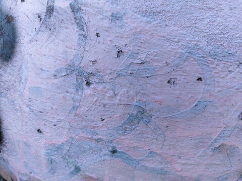 A soft pale pink and white textured surface marked by thin blue curved lines and cracks, forming abstract organic shapes across the slightly weathered paint layer.