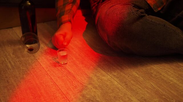 Man's hand reaches for a glass of alcohol.