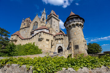 Historic castle in Austria surrounded by picturesque countryside and lush alpine scenery, presenting a timeless European architectural landmark beneath a dramatic sky. The elegant fortress © Yuliia