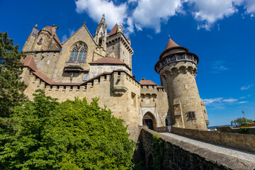 Historic castle in Austria surrounded by picturesque countryside and lush alpine scenery, presenting a timeless European architectural landmark beneath a dramatic sky. The elegant fortress © Yuliia
