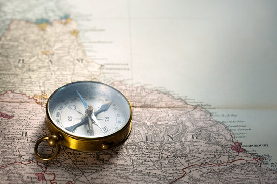 Antique compass on a 19th-century old map of Britain. Antique navigation instrument for travel, exploration, geography and discovery concept. 