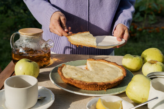 Woman serving slice of homemade apple pie at garden tea table