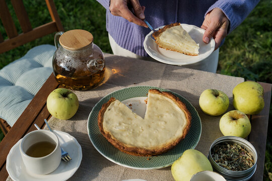 Woman serving slice of homemade apple pie at garden tea table